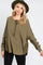 woman wearing an olive green long sleeve oversized henley top with a pocket and distressed detailing, paired with a hat