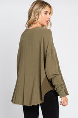 woman wearing an olive green oversized waffle knit top with dropped shoulders and raw hem, turned to the side