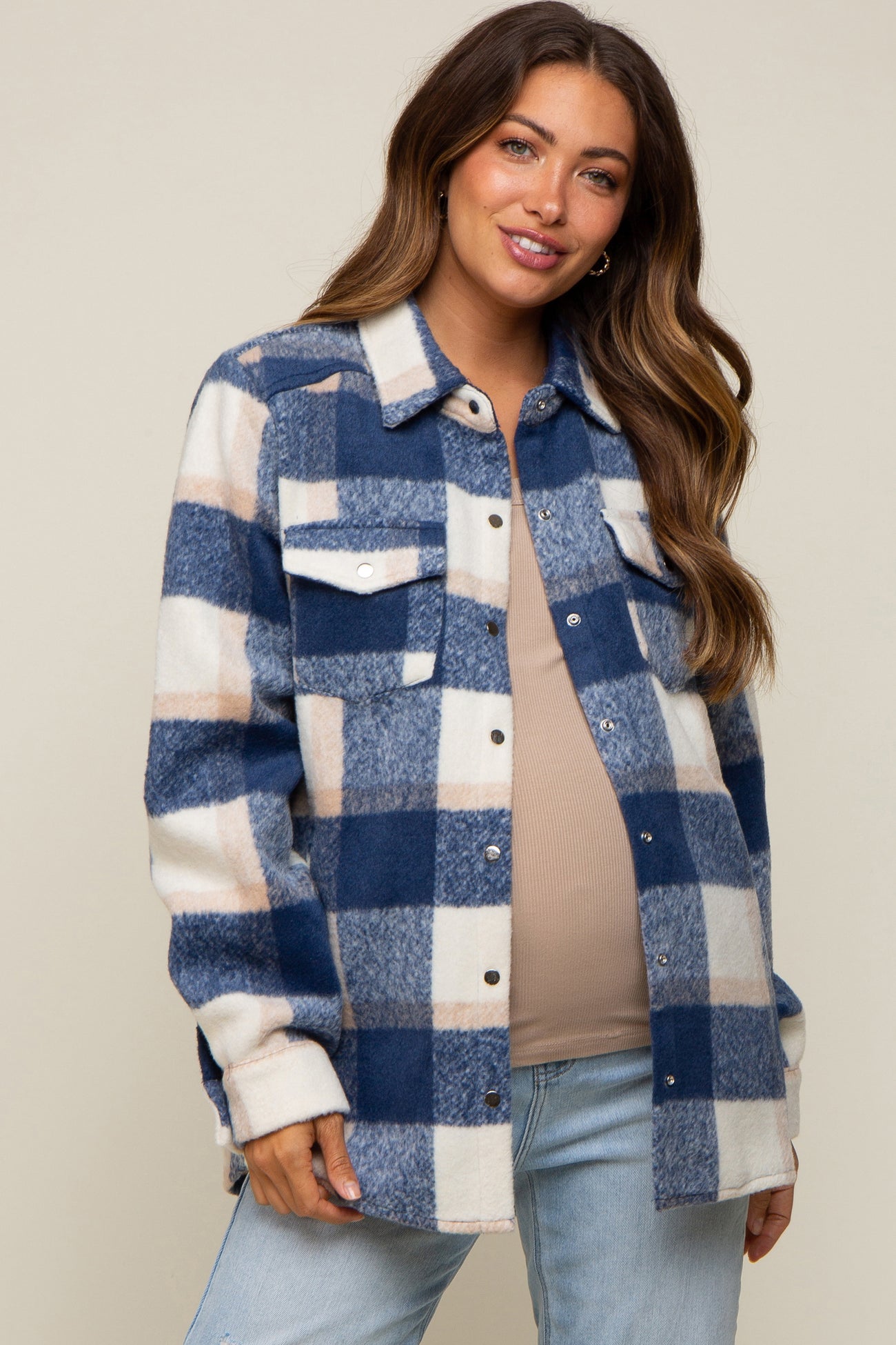 woman wearing a navy and white plaid maternity shirt jacket with a visible baby bump and light blue jeans