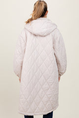 woman wearing a light pink quilted maternity coat with a hood and oversized sleeves, showing the back view
