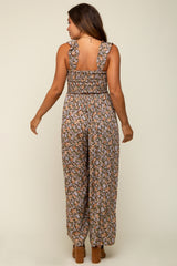 woman wearing a floral maternity jumpsuit with ruffled straps and wide legs, showing her back and a baby bump