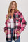 woman wearing a pink and black plaid flannel shirt jacket over a white tank top with front pockets and button closure