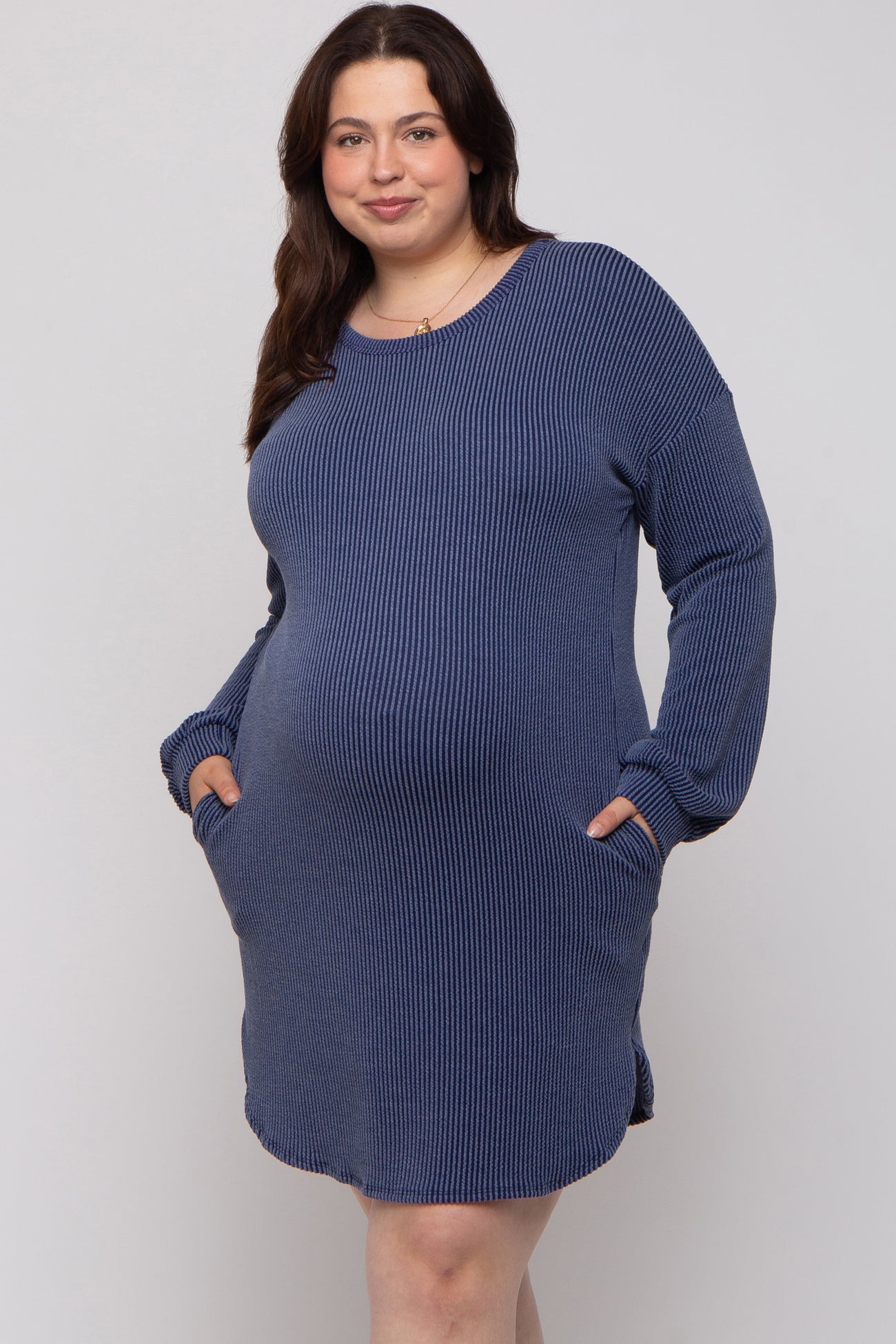 woman wearing a navy blue striped maternity dress with long sleeves and pockets, showing her baby bump