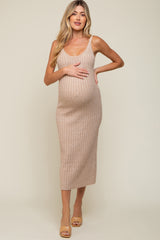 woman wearing a light brown ribbed maternity dress, showcasing her baby bump while posing with one hand on her belly