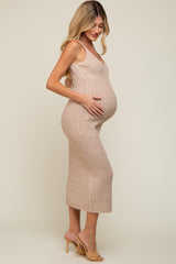 woman wearing a nude ribbed maternity dress and holding her baby bump, side view