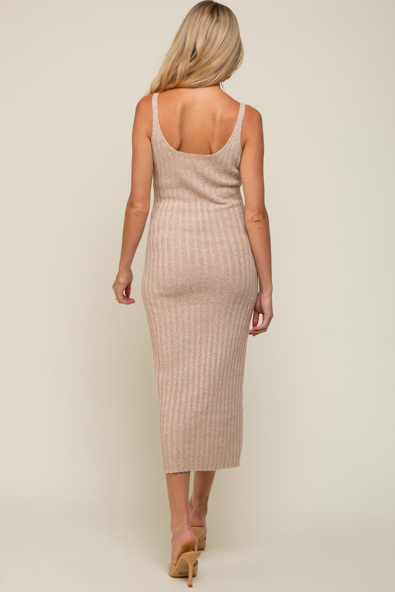 woman wearing a fitted ribbed maternity dress in beige, showcasing a back view with a midi length
