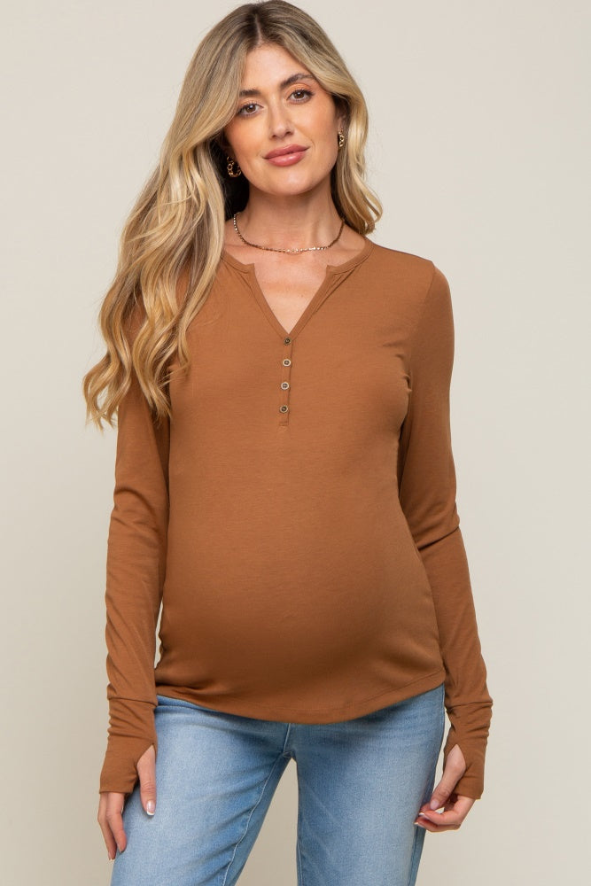 woman wearing a brown long sleeve maternity top with buttons and a visible baby bump