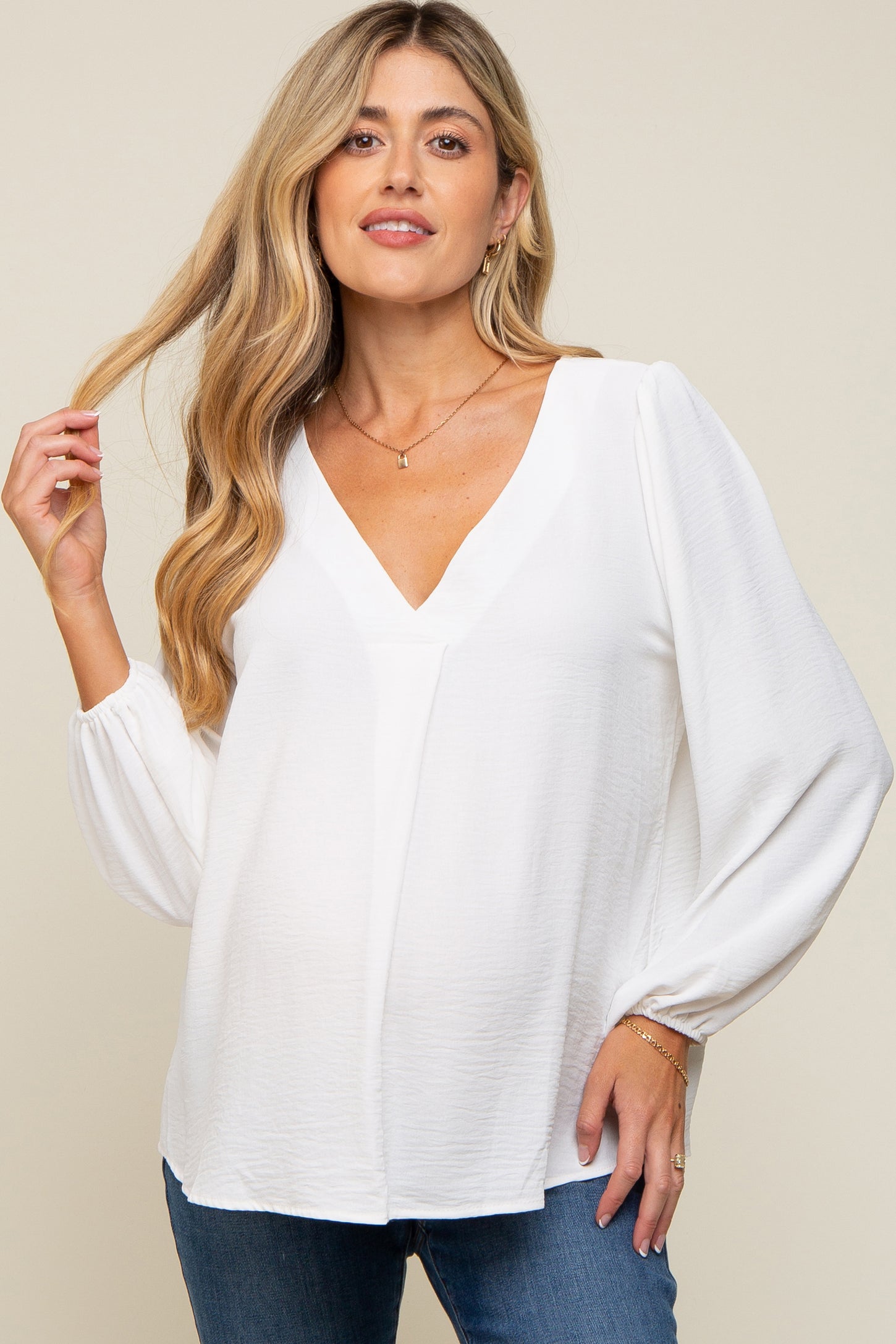woman wearing a white maternity top with a v-neck and puff sleeves, showing off her baby bump