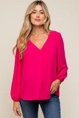 woman wearing a bright pink long sleeve maternity top with a v-neck and balloon sleeves, showcasing her baby bump