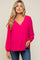 woman wearing a bright pink long sleeve maternity top with a v-neck and balloon sleeves, showcasing her baby bump