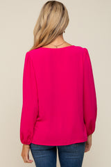 woman wearing a bright pink long sleeve maternity top with gathered sleeves, from the back, paired with blue jeans