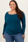 woman wearing a teal long sleeve top with a scoop neckline paired with blue jeans