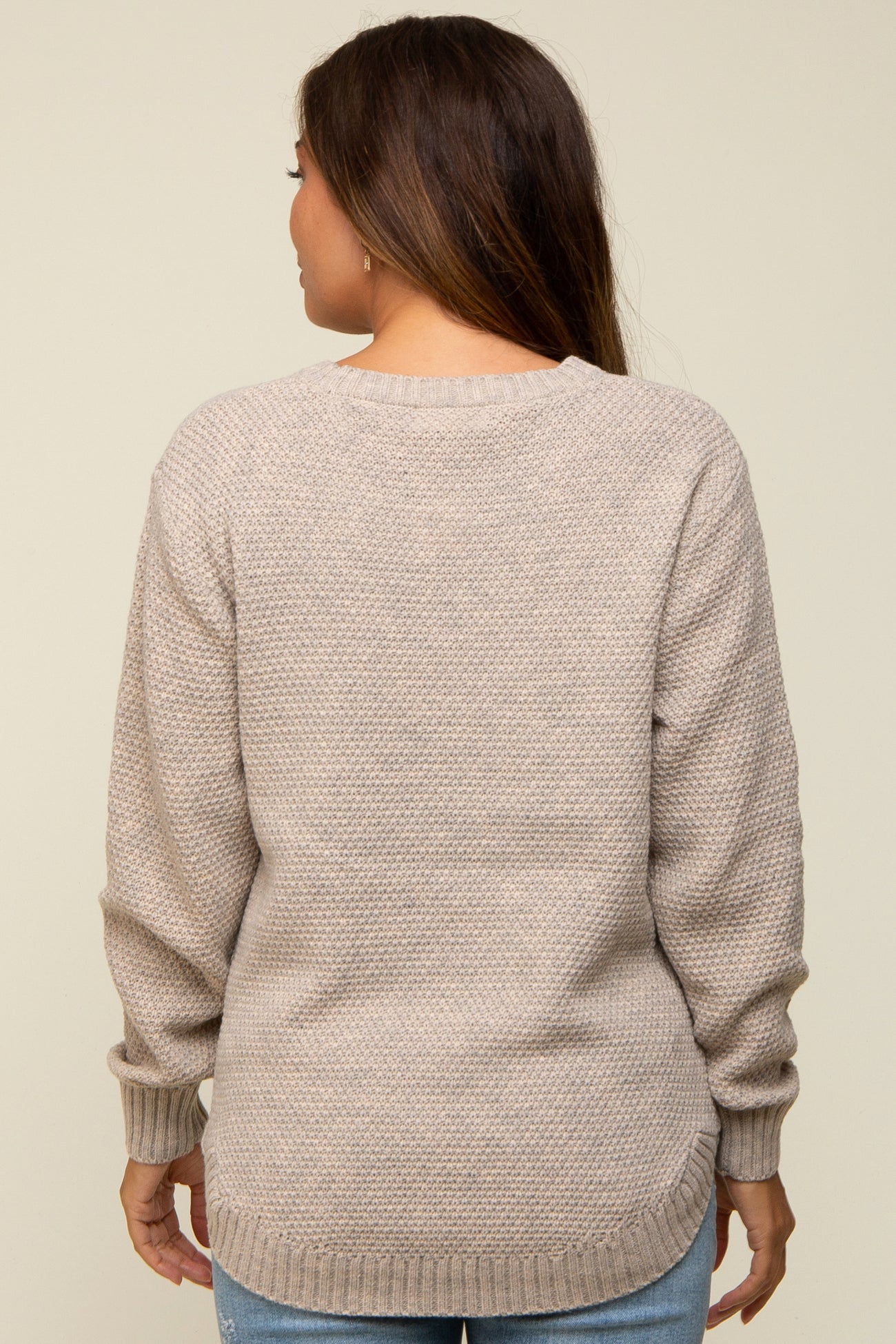 woman wearing a beige maternity sweater with a textured knit and relaxed fit, shown from the back