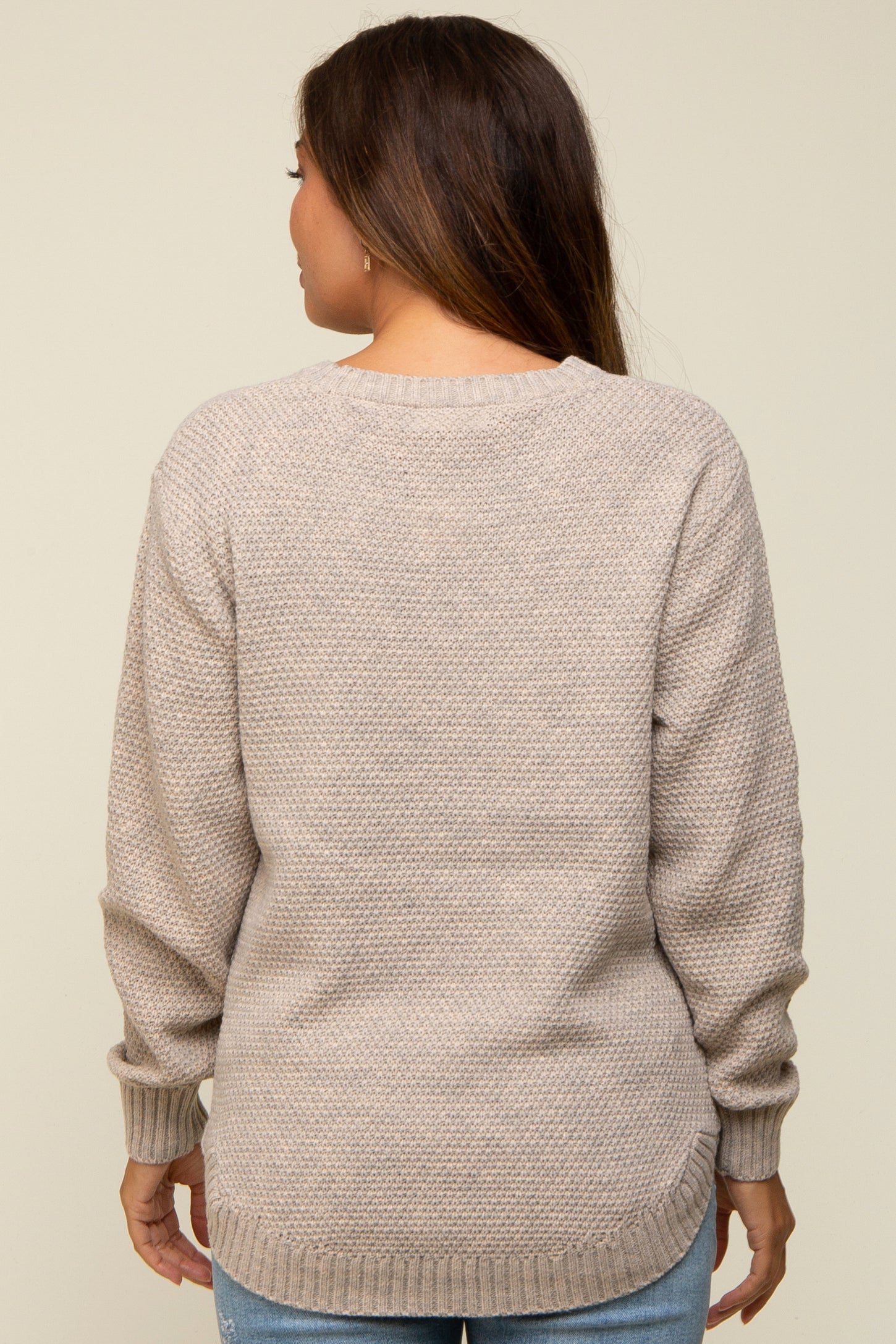 woman wearing a beige maternity sweater with a textured knit and relaxed fit, shown from the back
