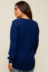 woman wearing a blue knit maternity sweater, shown from the back, paired with light blue jeans