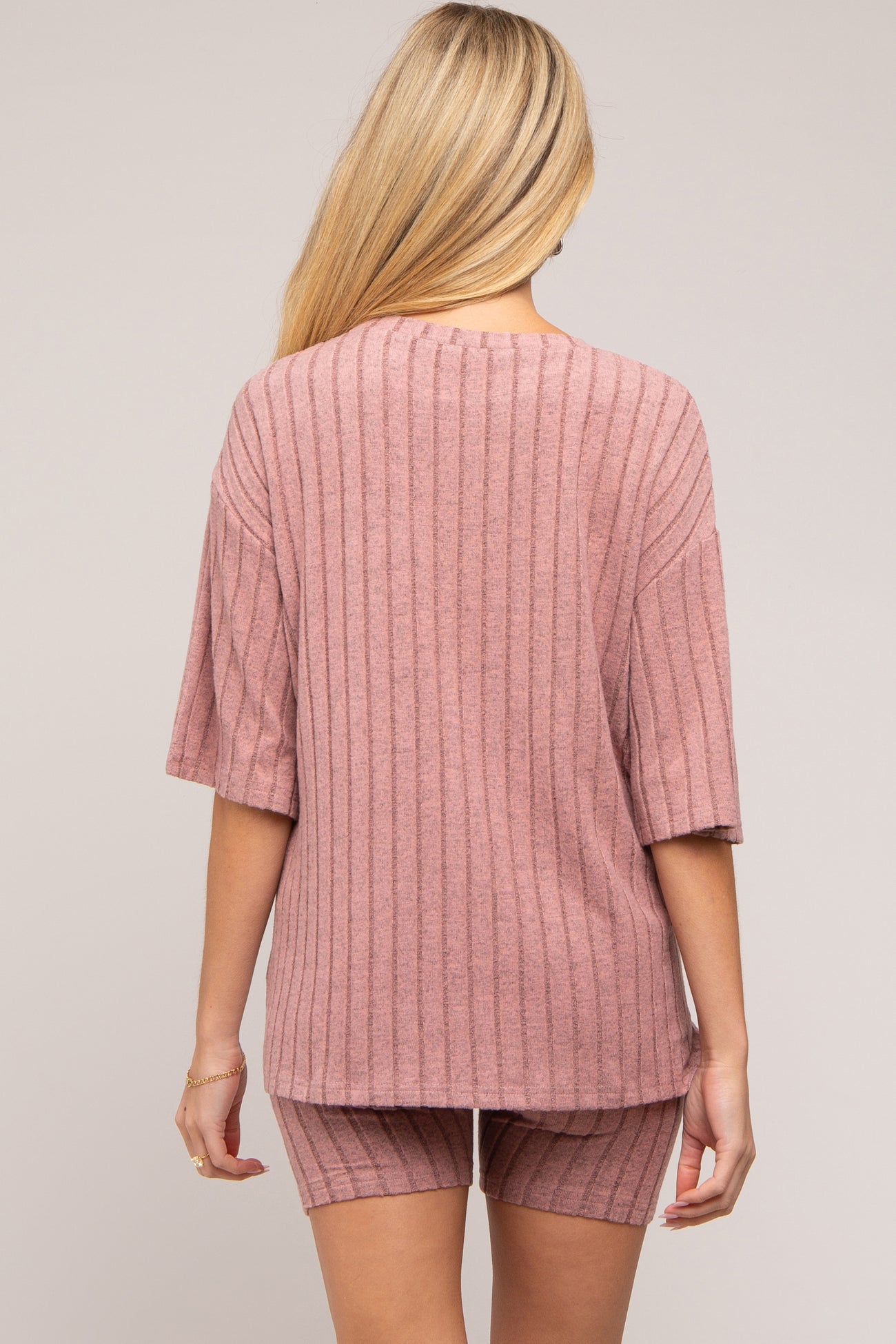woman wearing a dusty rose ribbed maternity top and matching shorts, viewed from the back