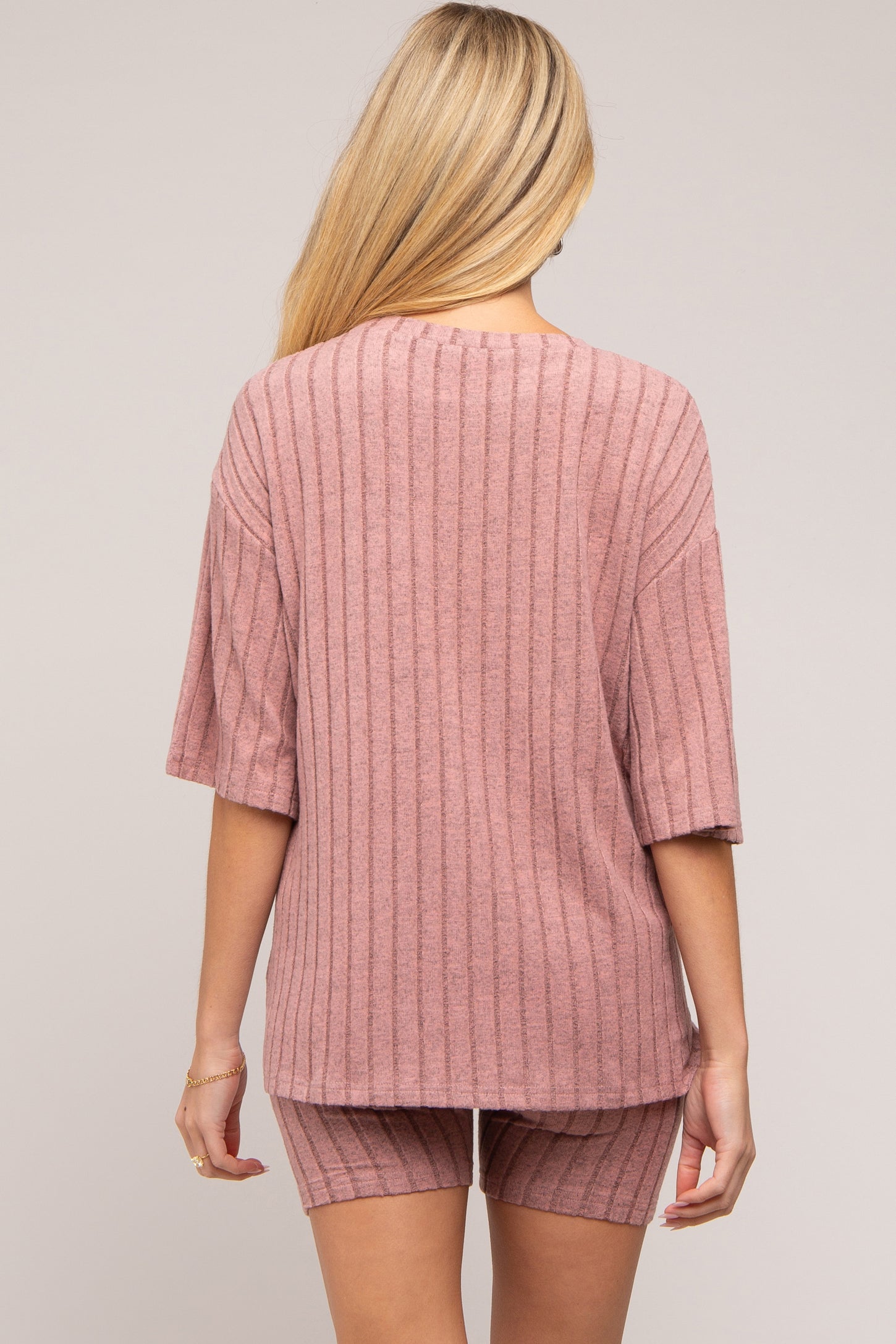 woman wearing a dusty rose ribbed maternity top and matching shorts, viewed from the back