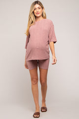 woman wearing a pink ribbed maternity short set with a loose top and shorts, showing her baby bump