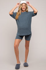 woman wearing a blue ribbed maternity pajama set with a loose top and shorts, showing her baby bump
