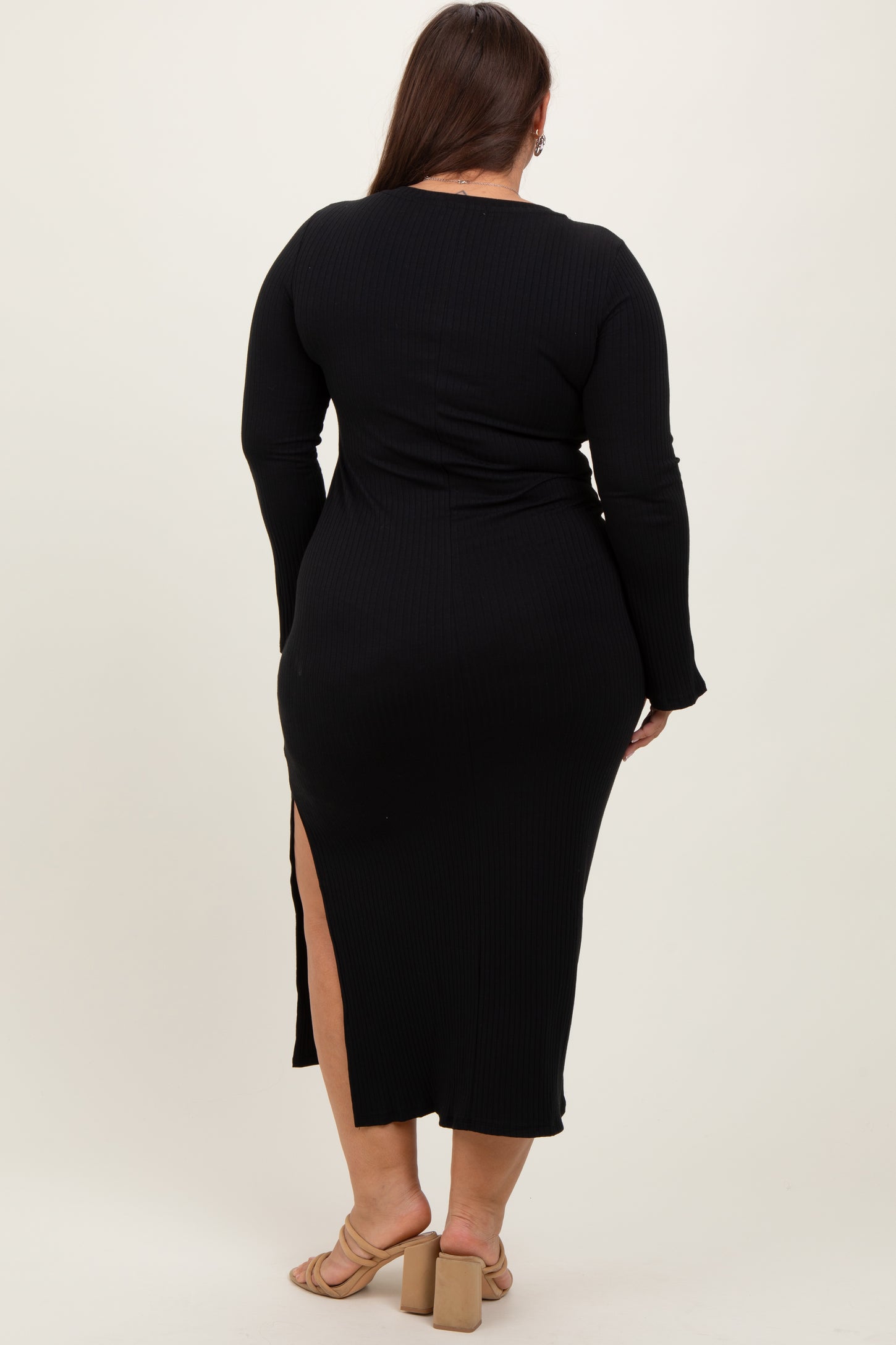 woman wearing a black long sleeve plus size dress with a thigh-high slit and fitted silhouette, viewed from the back