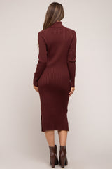 woman wearing a burgundy ribbed maternity dress with a turtleneck and side slits, shown from the back