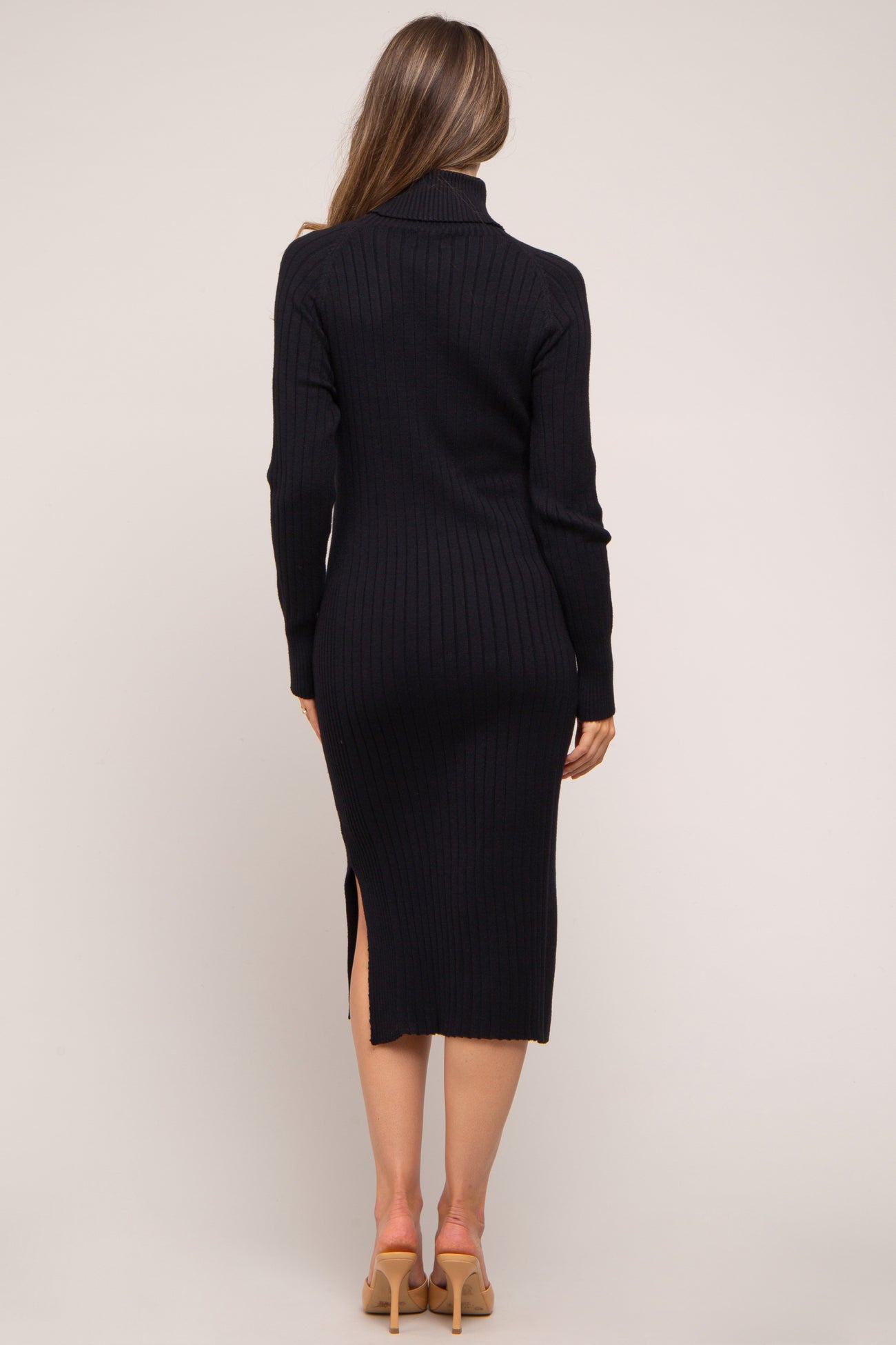 woman wearing a black ribbed maternity dress with a high neckline and side slit, showing a pregnant baby bump