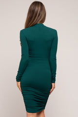 woman wearing a green long sleeve ruched maternity dress showcasing a baby bump from the back