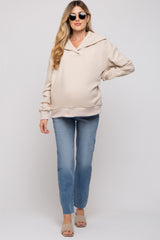 woman wearing a beige maternity hoodie with a loose fit and long sleeves, paired with light blue jeans and sunglasses, showcasing a baby bump