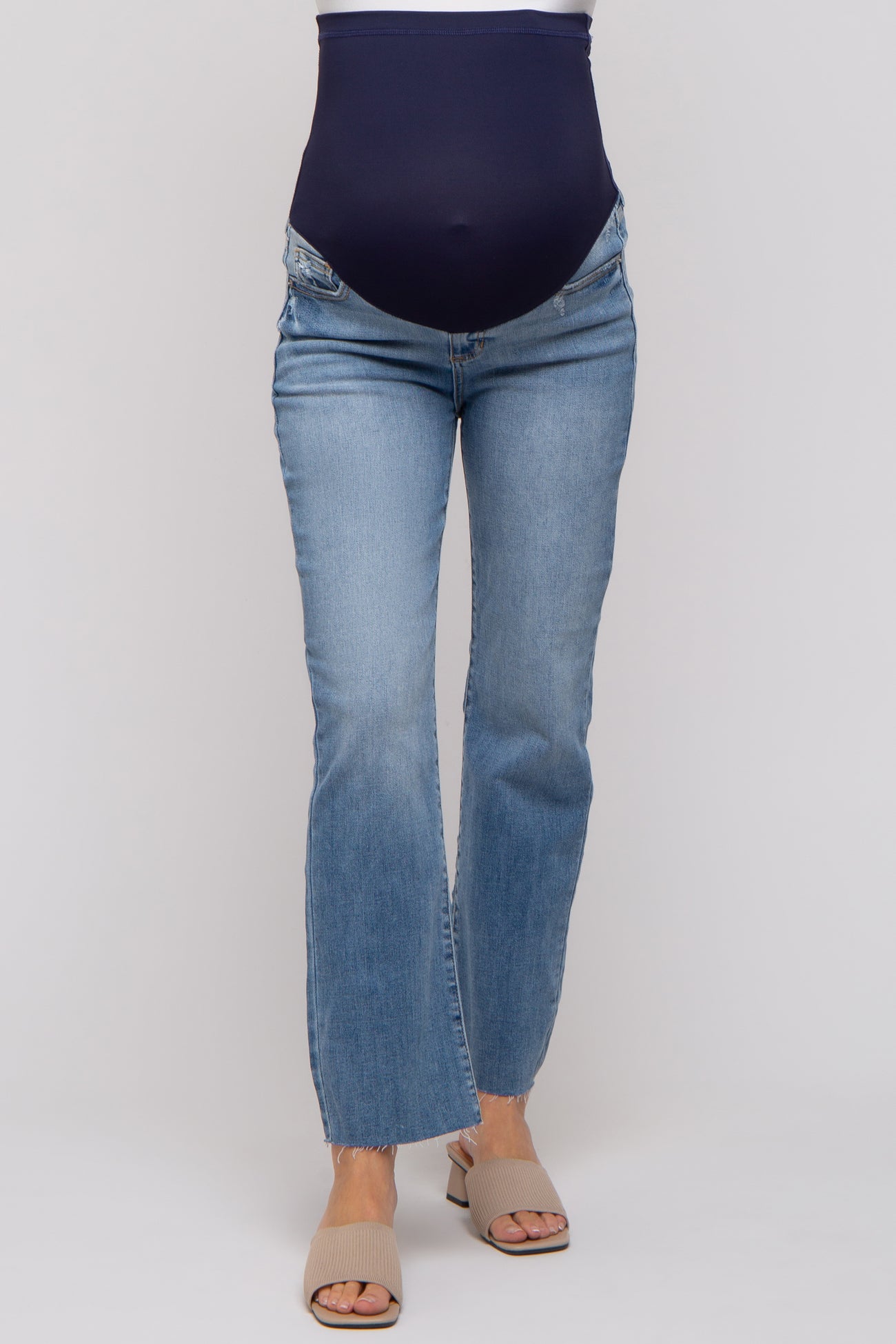 woman wearing light blue maternity jeans with a navy blue over-the-bump waistband and frayed hem detail