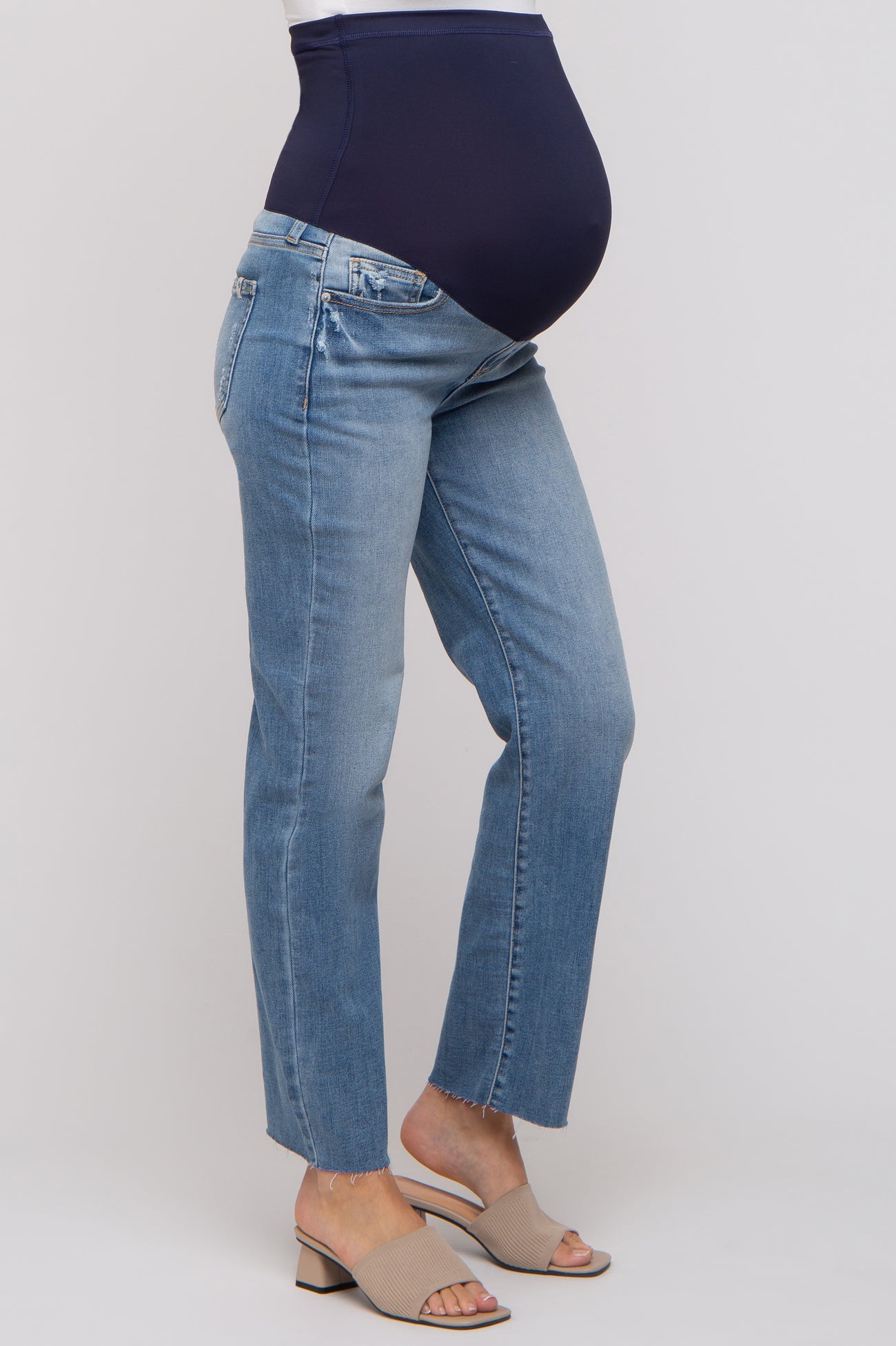 woman wearing light blue maternity jeans with a dark blue over-the-bump waistband and a visible baby bump