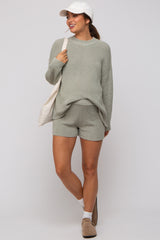 woman wearing a light green maternity sweater and shorts set with a cap and carrying a tote bag