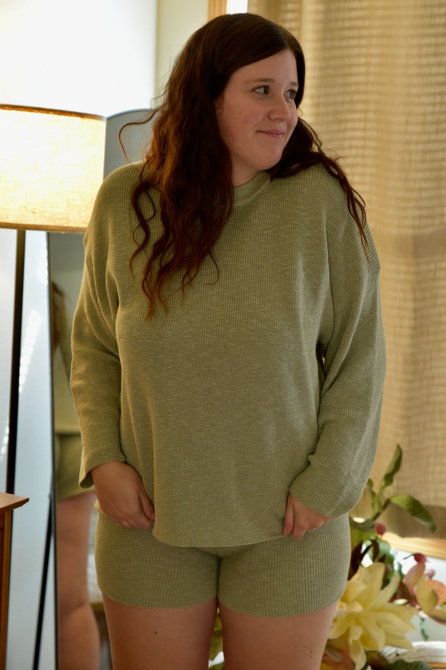 woman wearing a light green maternity short sleeve top and matching shorts, showing a baby bump