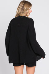 woman wearing a black oversized sweater with a loose fit and long sleeves, seen from the back