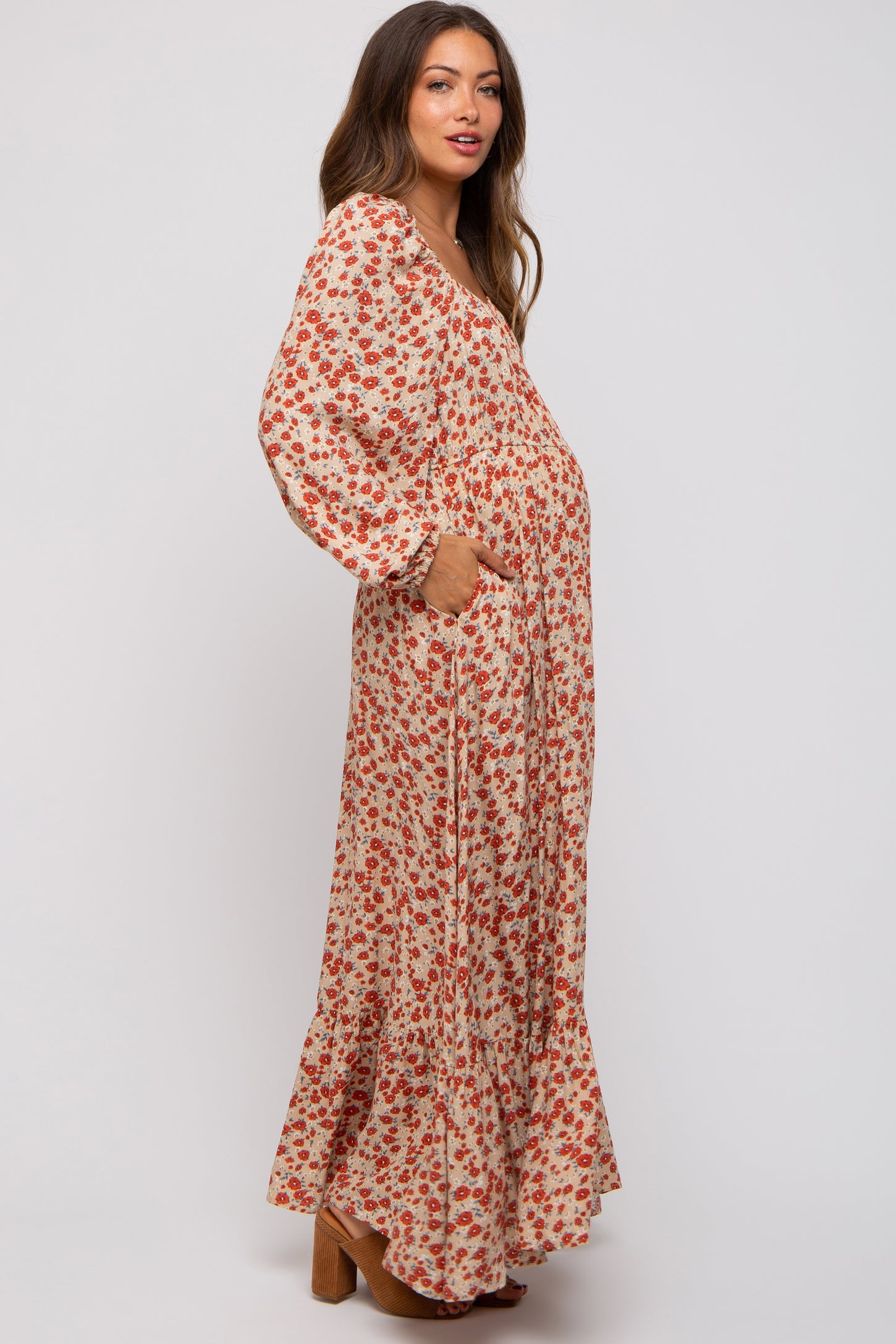 woman wearing a floral print maternity maxi dress with long sleeves and pockets, showing a baby bump