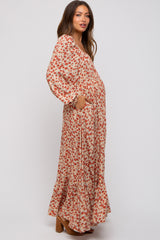 woman wearing a floral print maternity maxi dress with long sleeves and pockets, showing a baby bump