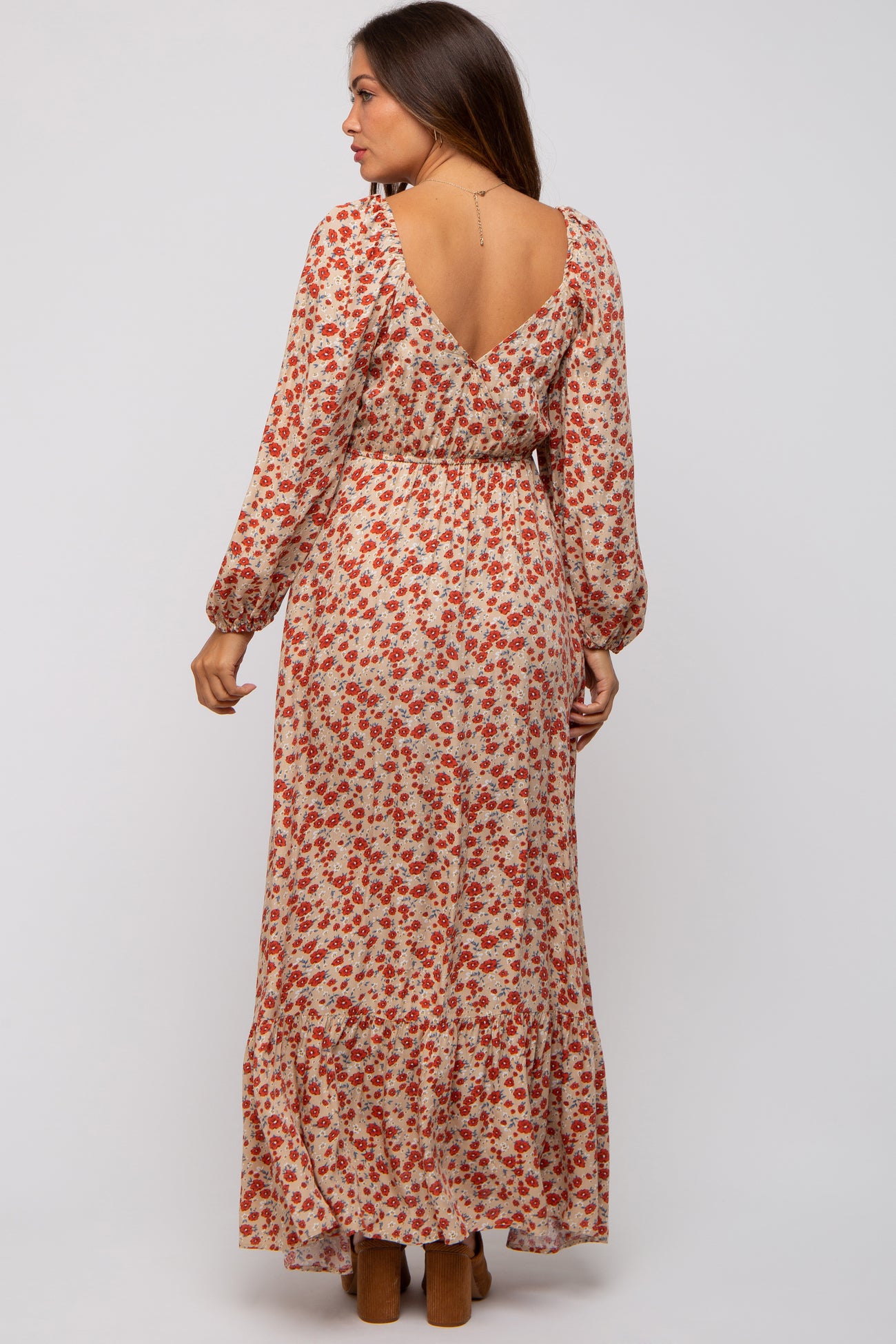 woman wearing a long sleeve floral maternity dress with a v-back and tiered hem, showcasing a baby bump