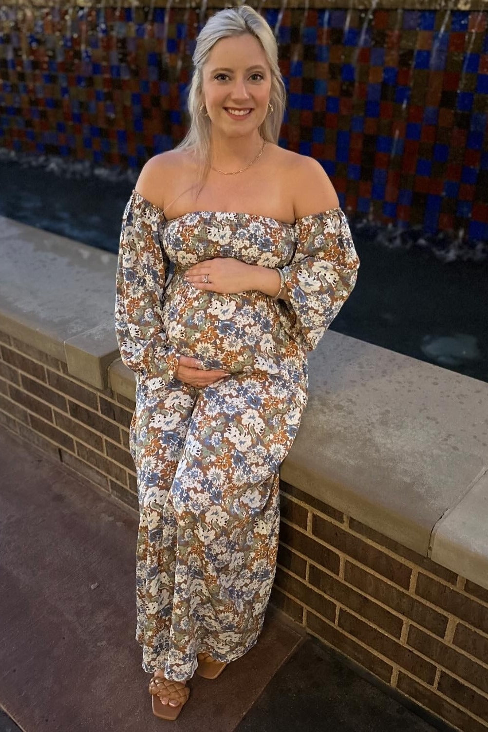 woman wearing a floral off-the-shoulder maternity maxi dress and holding her baby bump