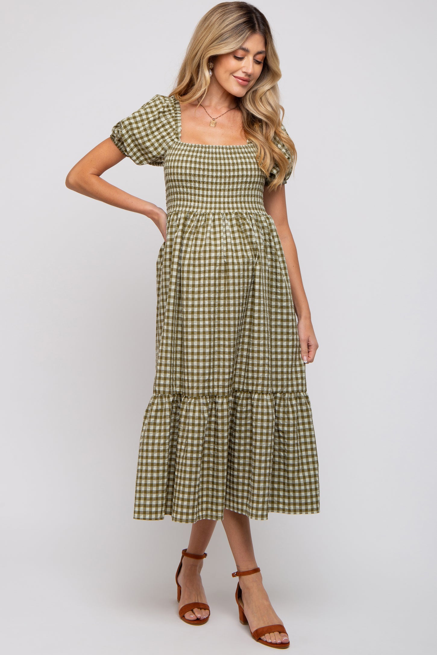 woman wearing a green and white checkered maternity dress with puff sleeves and a tiered hem