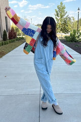 woman wearing a colorful knit cardigan over a light blue denim overall and beige slip-on shoes