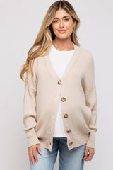 woman wearing a beige maternity cardigan with buttons, paired with a white t-shirt and blue jeans, showing a baby bump