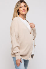 woman wearing a beige button-up maternity cardigan and showcasing her baby bump