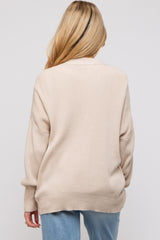 woman wearing a beige oversized maternity sweater, shown from the back, with a relaxed fit and ribbed details