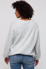 woman wearing a gray oversized sweatshirt with a relaxed fit and back view, paired with blue jeans