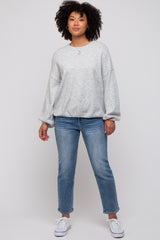 woman wearing a grey oversized sweatshirt with a v-neck and blue straight-leg jeans