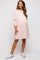 woman wearing a light pink long sleeve maternity dress with a side slit and a visible baby bump