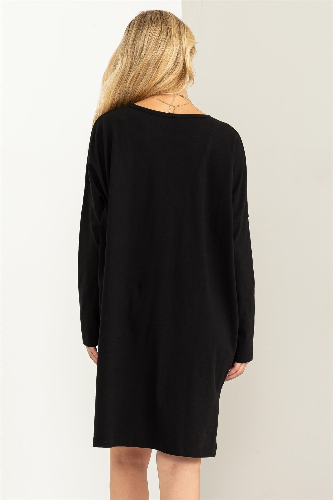 woman wearing a black long sleeve oversized dress, viewed from the back