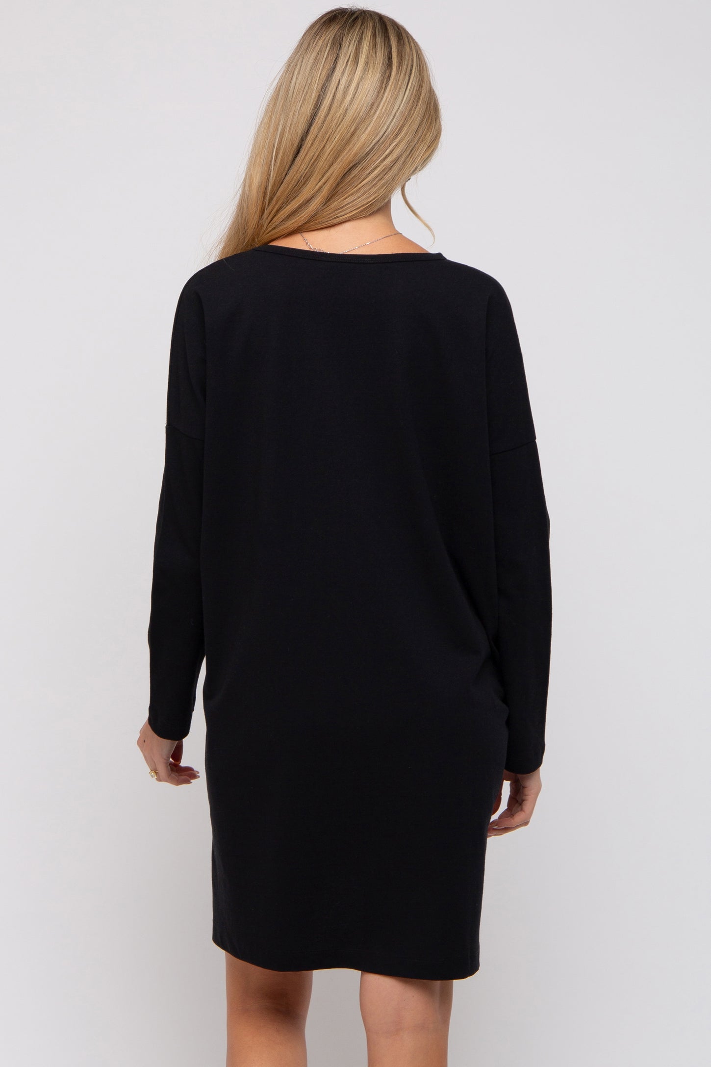 woman wearing a black long sleeve maternity dress, showing the back view and relaxed fit