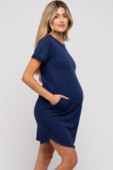 woman wearing a navy blue short sleeve maternity dress with side pockets and a visible baby bump