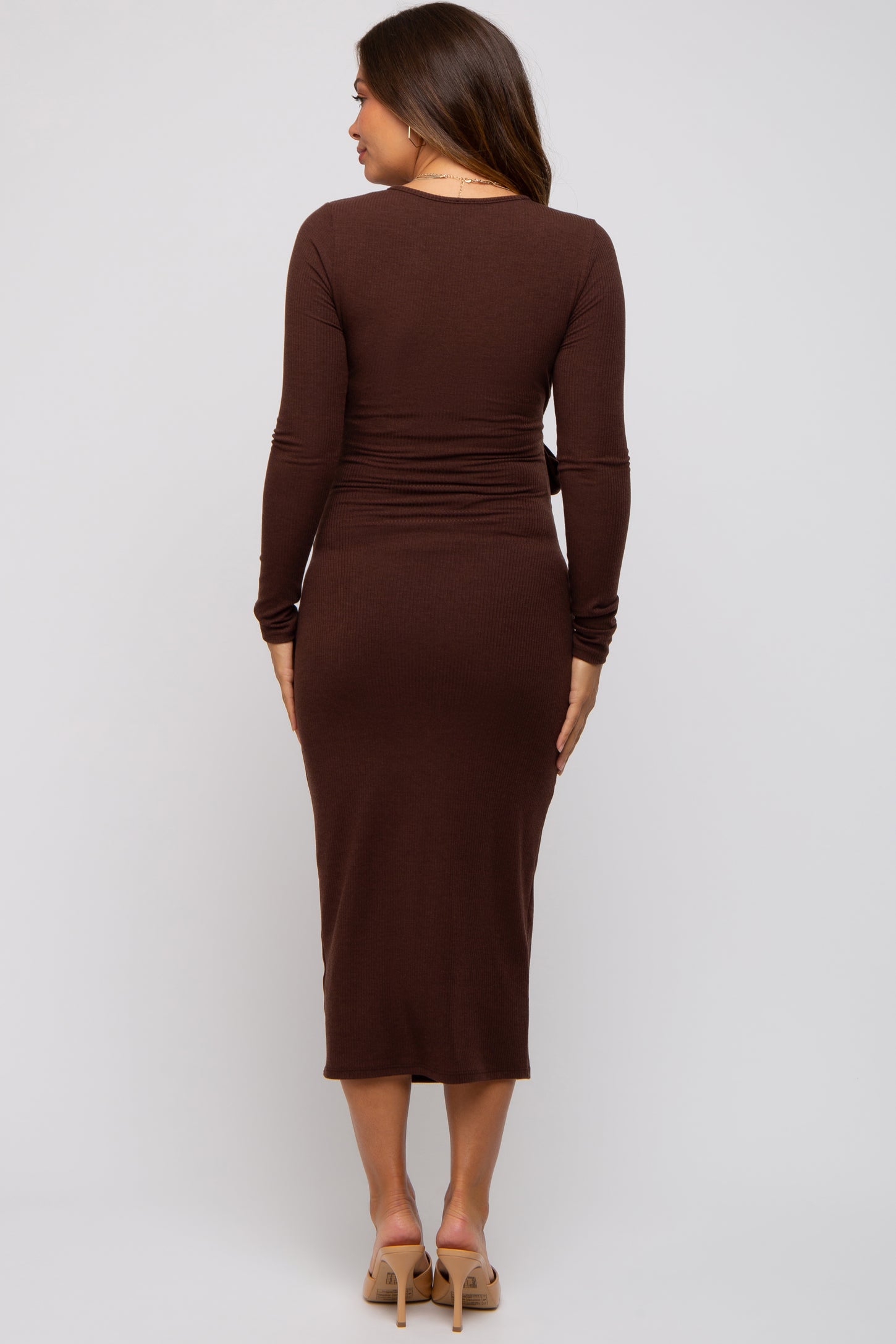 woman wearing a brown long sleeve maternity dress with a fitted waist and midi length from the back