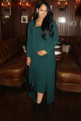 woman wearing a dark green maternity dress with a matching long cardigan and holding her baby bump